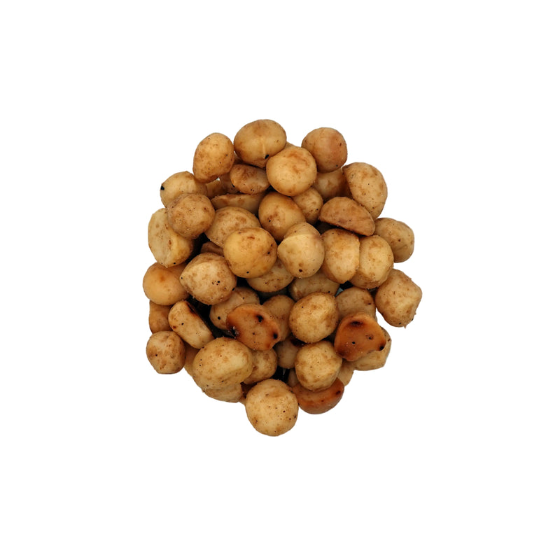 A top-down view of roasted salted macadamias in a clear glass bowl on a white background.