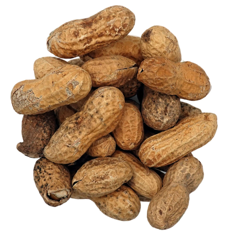 A top-down view of unsalted in-shell peanuts in their natural tan and brown shells, presented in a small clear glass bowl on a clean white background.