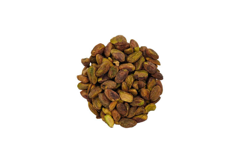 A top-down view of roasted pistachios in a clear glass bowl on a white background.