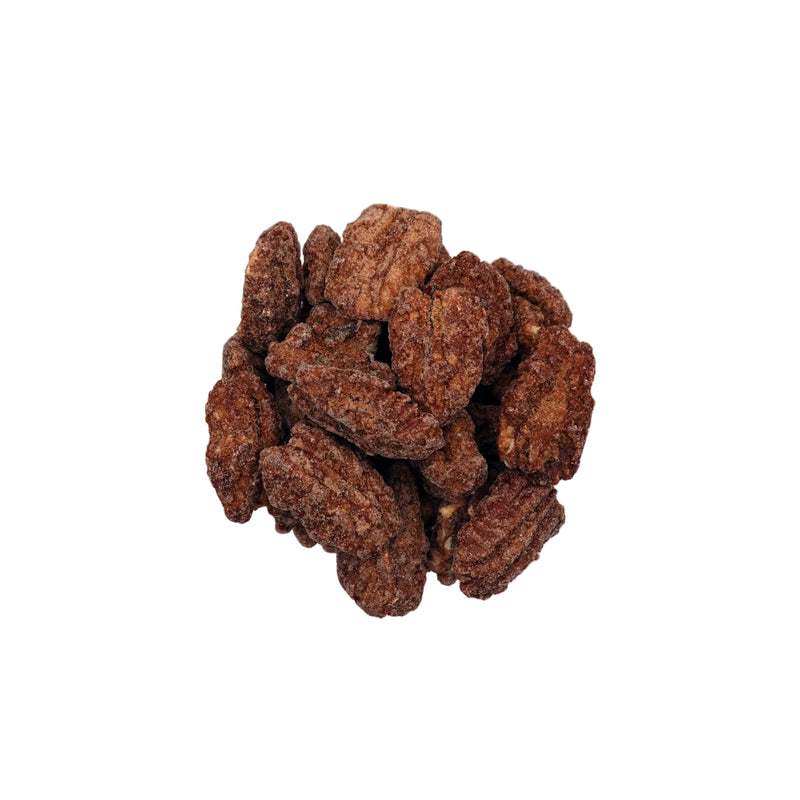 A top-down view of cinnamon glazed pecans piled in a clear glass bowl on a white background.