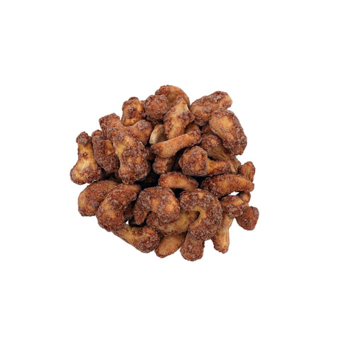 Cinnamon glazed cashews piled in a clear glass bowl, photographed from directly above on a clean white background.