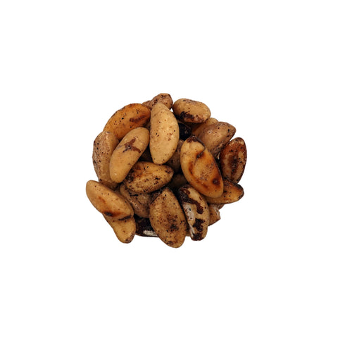 Roasted and salted brazil nuts in a clear glass bowl, photographed from a top-down view on a plain white background.