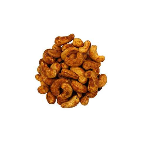 A top-down view of roasted old bay cashews in a clear glass bowl, centered on a plain white background.
