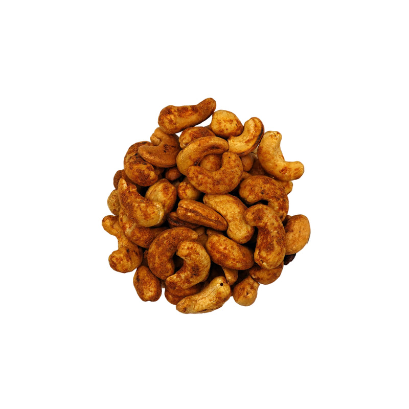 A top-down view of roasted old bay cashews in a clear glass bowl, centered on a plain white background.
